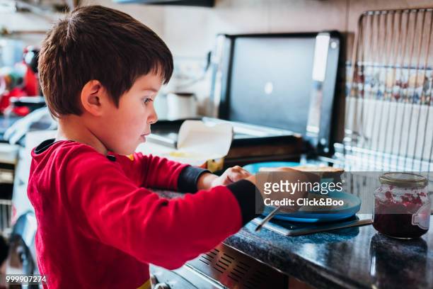 cute little boy preparing a toasted bread in a kitchen - raspberry jam stock pictures, royalty-free photos & images