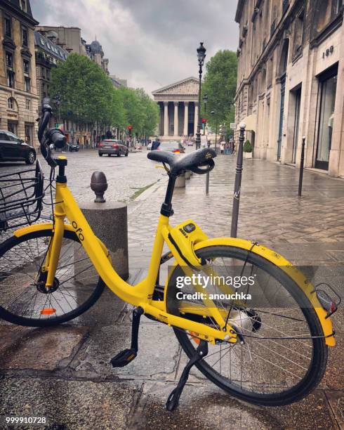 vélo stationné sur la rue mouillée après la pluie dans le centre de ville de paris, france - quartier de la madeleine photos et images de collection