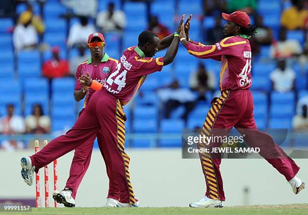 West Indies crickter Kemar Roach celebrates with team captain Chris Gayle after bowling out South African crickter Jean-Paul Duminy during the first...