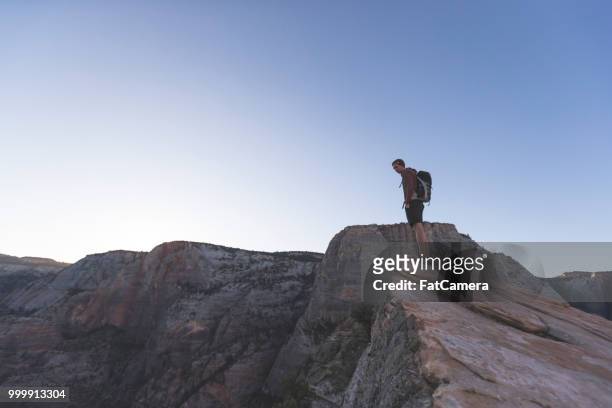 ein männlicher wanderer steht am rande einer felswand - valley side stock-fotos und bilder