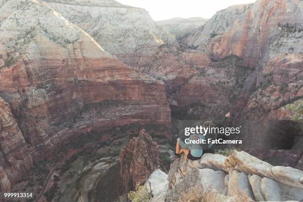 zwei frauen wanderer sitzen am rand einer klippe - valley side stock-fotos und bilder