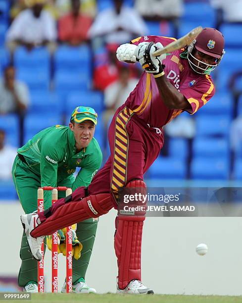 West Indies cricket team captain Chris Gayle hits a boundary as South African wicketkeeper AB de Villiers looks on during the first T20 match between...