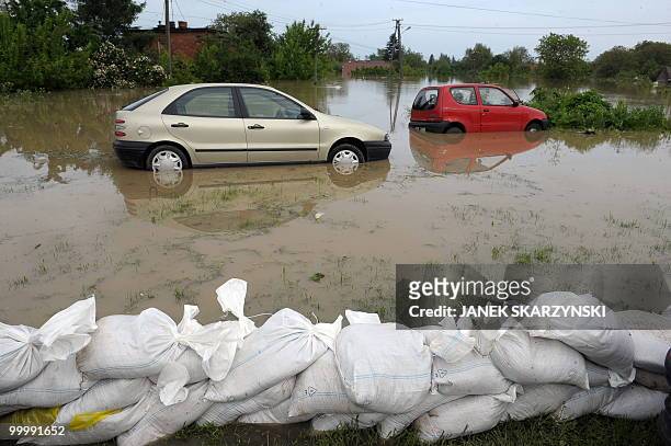 Flooded cars are pictured behind a sand fence in the flooded district of Sandomierz, central Poland, on May 19, 2010. The floods striking southern...