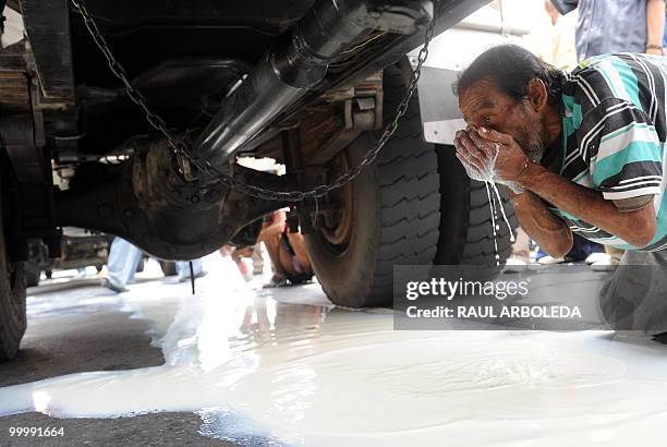Man drinks milk that fell onto the ground after dairy farmers distributed free milk during a demonstration on May 19, 2010 in Medellin, Antioquia...