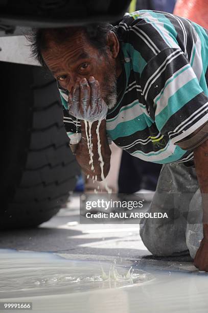 Man drinks milk that fell onto the ground after dairy farmers distributed free milk during a demonstration on May 19, 2010 in Medellin, Antioquia...