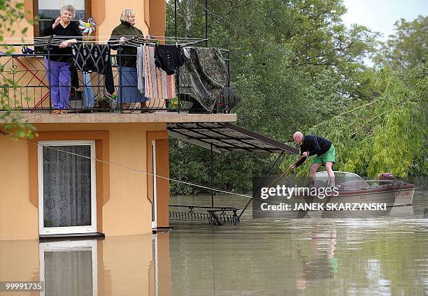 Elderly women residents stand on their balcony as a man makes his way in a small boat in the flooded district of Sandomierz, central Poland, on May...