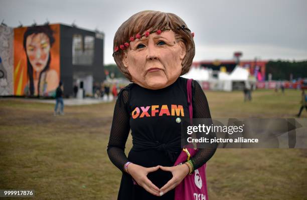 Dpatop - An activist wears a mask of the German chancellor Angela Merkel and an Oxfam shirt at the Lollapalooza festival in Hoppegarten, Germany, 9...