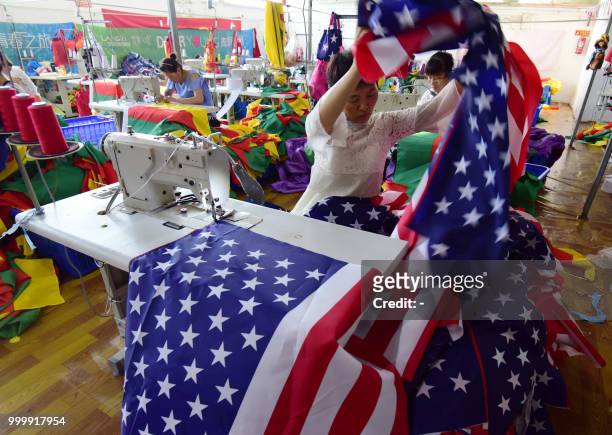 This photo taken on July 13, 2018 shows a Chinese employee sewing a US flag at a factory in Fuyang in China's eastern Anhui province. - As the...