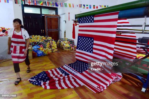 This photo taken on July 13, 2018 shows a Chinese employee walking past newly made US flags at a factory in Fuyang in China's eastern Anhui province....