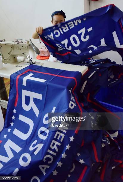 This photo taken on July 13, 2018 shows a Chinese employee sewing a banner declaring US President Donald Trump's re-election intentions that reads...