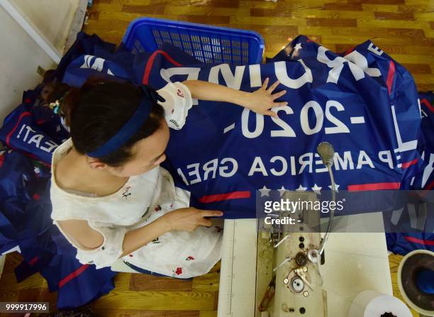 This photo taken on July 13, 2018 shows a Chinese employee sewing a banner declaring US President Donald Trump's re-election intentions that reads...