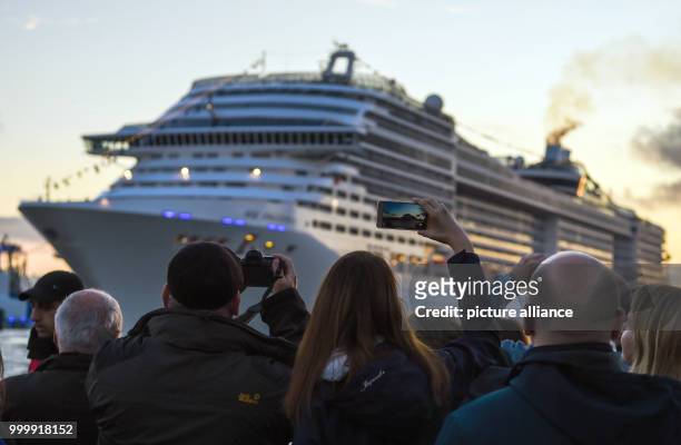 Visitors look at the passing cruise ship 'MSC Preziosa' during the cruise festival Hamburg Cruise Days at the Elbe river in Hamburg, Germany, 9...