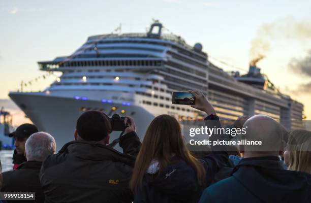 Dpatop - Visitors look at the passing cruise ship 'MSC Preziosa' during the cruise festival Hamburg Cruise Days at the Elbe river in Hamburg,...