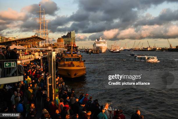 Visitors look at the passing cruise ships next to the Elbphilharmonie concert hall during the cruise festival Hamburg Cruise Days at the Elbe river...