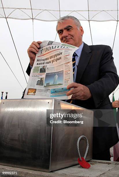 Athanasios Orphanides, governor of the Central Bank of Cyprus, holds a Greek newspaper during a ceremony to lay the cornerstone for the new ECB...