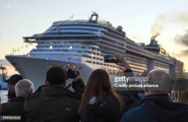 Visitors look at the passing cruise ship 'MSC Preziosa' during the cruise festival Hamburg Cruise Days at the Elbe river in Hamburg, Germany, 9...