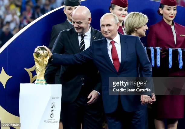 President of Russia Vladimir Putin touches the trophy while FIFA President Gianni Infantino looks on during the trophy ceremony following the 2018...