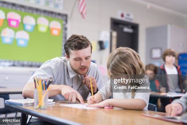 leraar helpen een 1e rang meisje op haar bureau - advance 2018 exam stockfoto's en -beelden