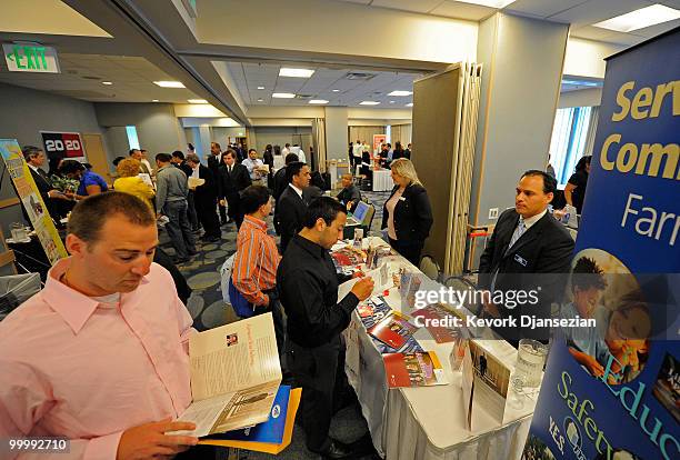 Job seekers drop their resumes and pick brochures at the Farmers Insurance table during a job fair held by National Career Fair on May 19, 2010 in...