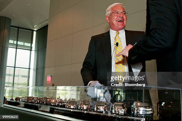 Robert "Bob" Lutz, former vice chairman of General Motors Co., laughs as he is presented with a case containing models of GM cars that were designed...