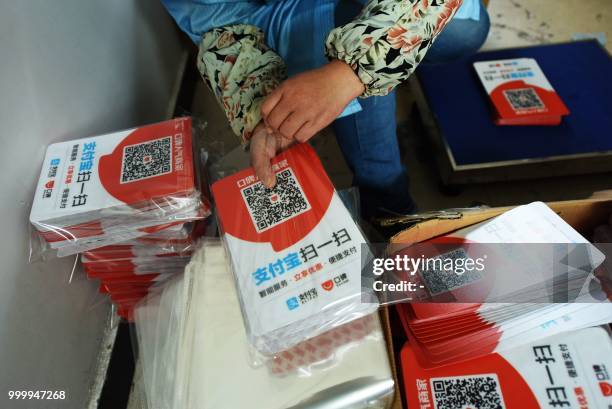 Worker packs newly printed cards showing Alipay QR codes for online payment at a printing factory in Hangzhou in China's eastern Zhejiang province on...