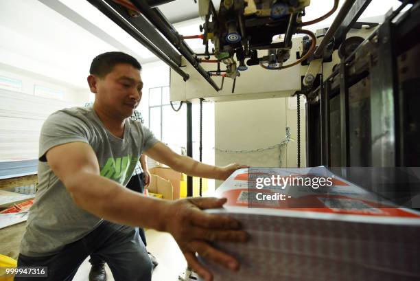 Worker holds newly printed cards showing Alipay QR codes for online payment at a printing factory in Hangzhou in China's eastern Zhejiang province on...