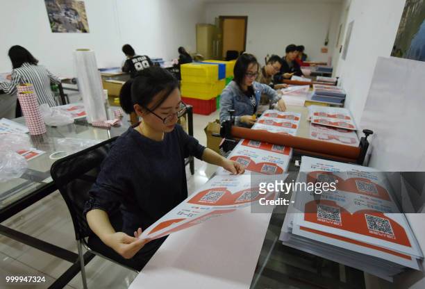Workers check newly printed cards showing Alipay QR codes for online payment at a printing factory in Hangzhou in China's eastern Zhejiang province...