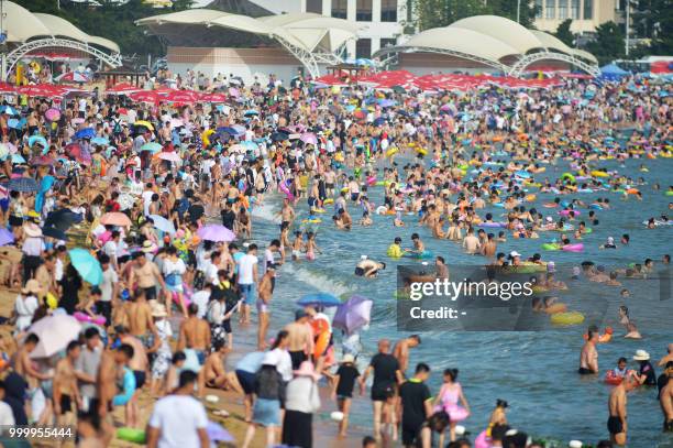 This photo taken on July 14, 2018 shows people cooling off on a beach amid high temperatures in Qingdao, east China's Shandong province. / China OUT