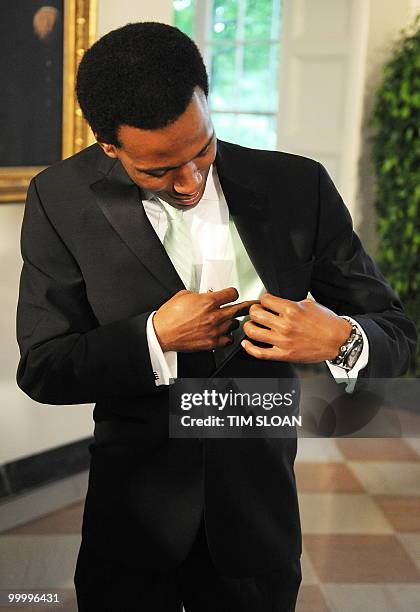 Speed skating gold medalist Shani Davis looks inside his suit to answer the question "who is your suit by" as he rrives for the State Dinner in honor...
