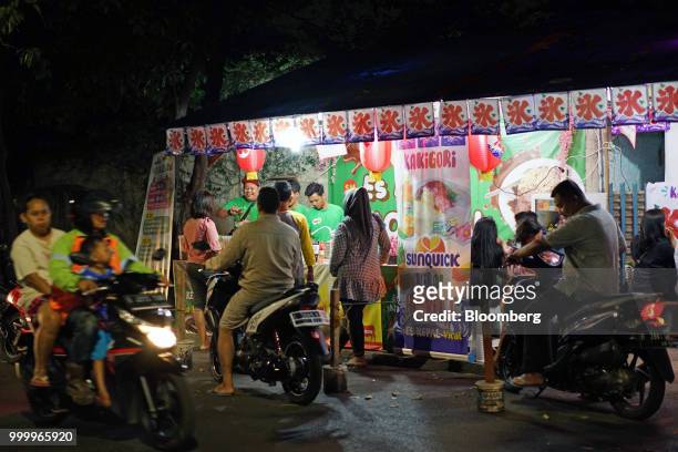 Motorcyclists pass customers waiting while ordering the Milo on round ice snack at an Es Kepal Milo Viral street stall at night in the Tebet area of...