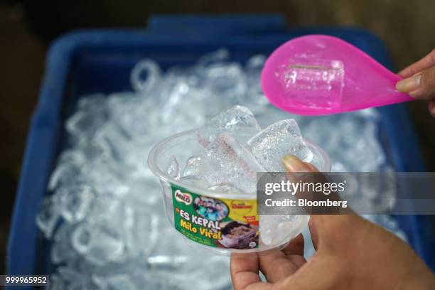 Vendor scoops up a bowl of ice while preparing a Milo on round ice snack at an Es Kepal Milo Viral street stall in the Tebet area of Jakarta,...