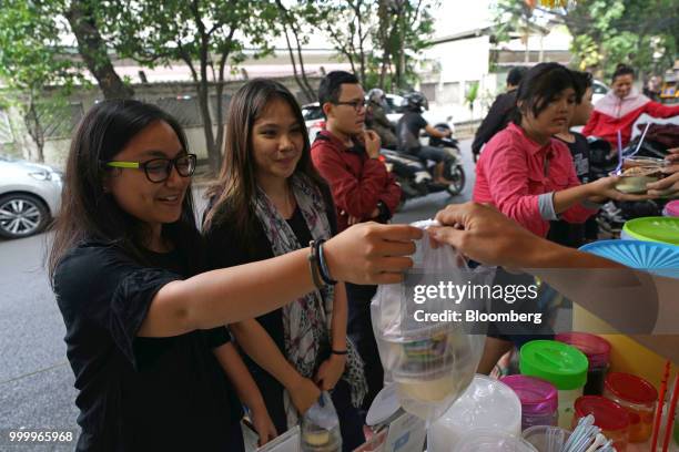 Customer receives a take-out bag of Milo on round ice snack at an Es Kepal Milo Viral street stall in the Tebet area of Jakarta, Indonesia, on...