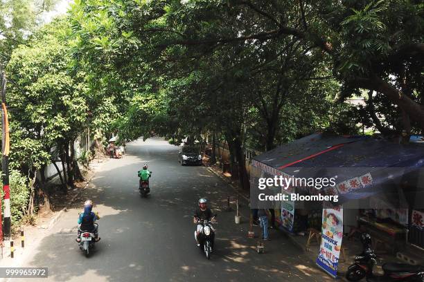 Motorcyclists ride past customers ordering the Milo on round ice snack at an Es Kepal Milo Viral street stall in the Tebet area of Jakarta,...