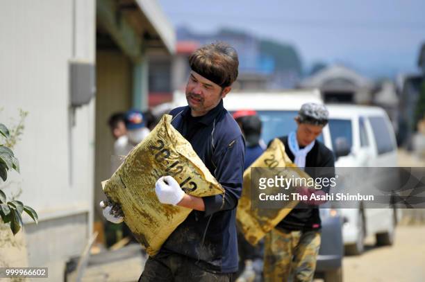 People carry bags from a submerged house on July 15, 2018 in Kurashiki, Okayama, Japan. More than 100 people were treated for heatstroke as scorching...
