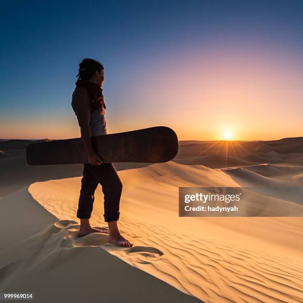 mujer joven sandboard en el desierto del sahara durante la puesta del sol, áfrica - desierto libio fotografías e imágenes de stock