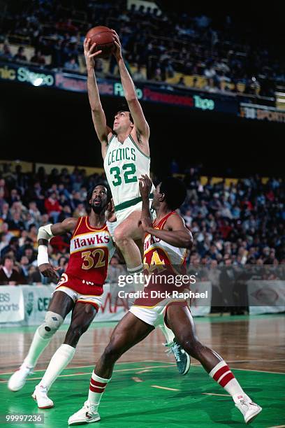 Kevin McHale of the Boston Celtics shoots takes the ball to the basket against Dan Roundfield and Mike Glenn of the Atlanta Hawks during a game...