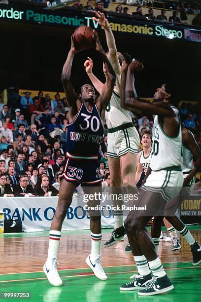 Bernard King of the New York Knicks shoots against Larry Bird and Robert Parish of the Boston Celtics during a game played in 1983 at the Boston...