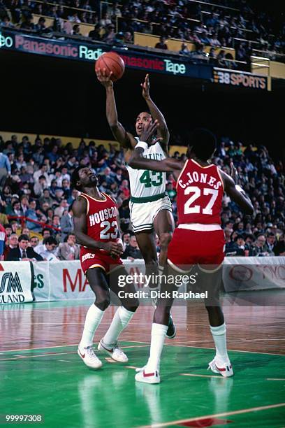 Gerald Henderson of the Boston Celtics shoots a layup against Caldwell Jones and Calvin Murphy of the Houston Rockets during a game played in 1983 at...