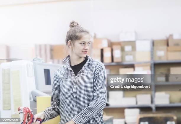 woman using a masking tape gun in a warehouse - tape dispenser photos et images de collection