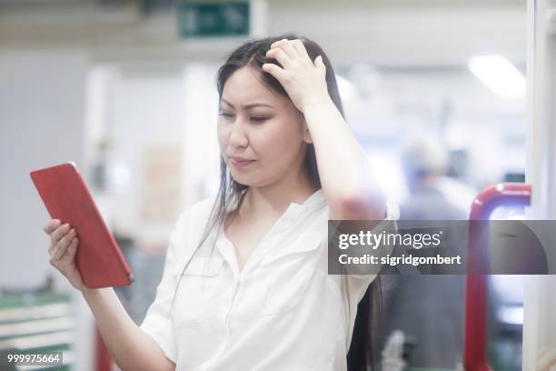 female engineer looking at technical drawings on a digital tablet, scratching her head - sich am kopf kratzen stock-fotos und bilder