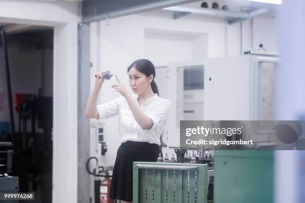 female engineer examining a drill bit - drill bit stockfoto's en -beelden