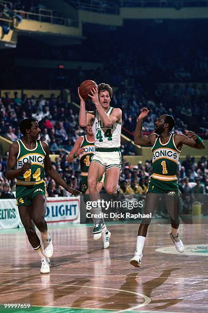 Danny Ainge of the Boston Celtics looks to make a play against David Thompson and Gus Williams of the Seattle Supersonics during a game played in...