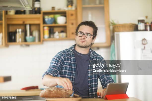 man standing in kitchen slicing a loaf of bread - loaf stock pictures, royalty-free photos & images