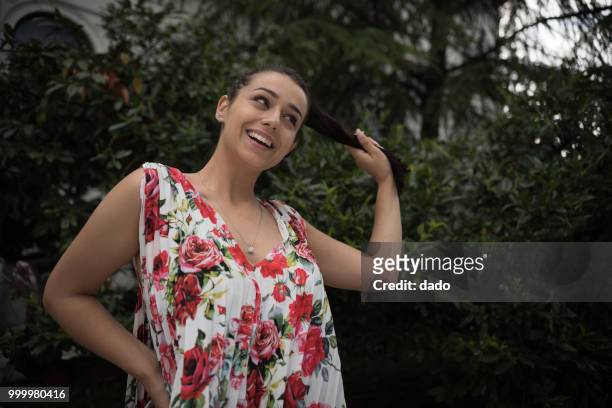 smiling woman standing in a garden holding her hair - dado stock pictures, royalty-free photos & images