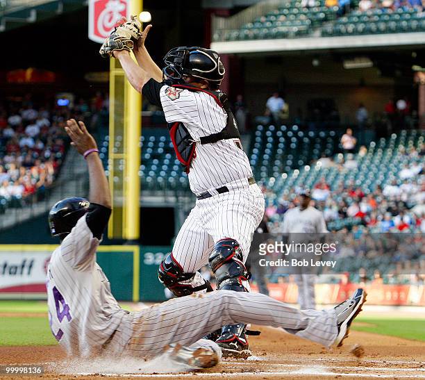 Dexter Fowler of the Colorado Rockies scores in the first inning as catcher Kevin Cash of the Houston Astros takes the high throw at Minute Maid Park...