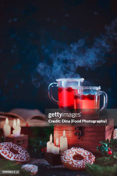 two cups of berry hot drink in a night scene with gingerbread and candles. holiday cooking... - berry stock-fotos und bilder