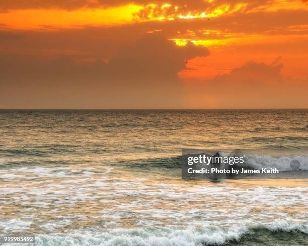 a lone surfer enjoys a ride as the sun rises on playalinda beach, canaveral national seashore. - cabo cañaveral fotografías e imágenes de stock