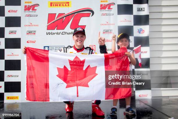 Scott Hargrove of Canada holds the Canadian flag with a young fan after the Pirelli World Challenge GT race at Portland International Raceway on July...
