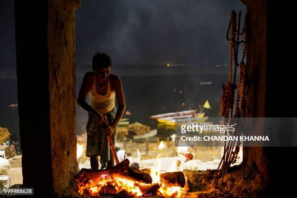 In this photograph taken on June 1, 2018 an Indian man tends a "sacred fire" that is maintained by members of the Dom community and given to Doms to...
