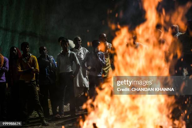 In this photograph taken on June 2, 2018 Indian men wait for a dead body to finish being cremated at the Manikarnika Ghat in the old quarters of...